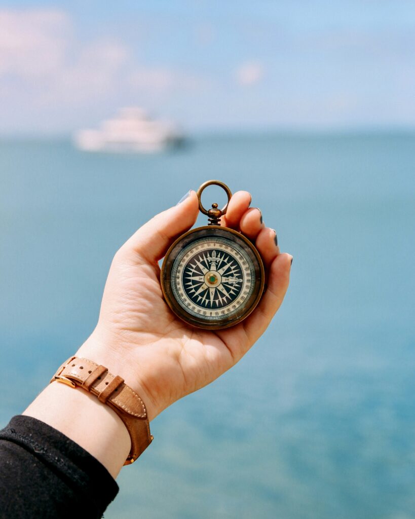 mão segurando bússola vintage sobre o mar - transições de vida e psicologia